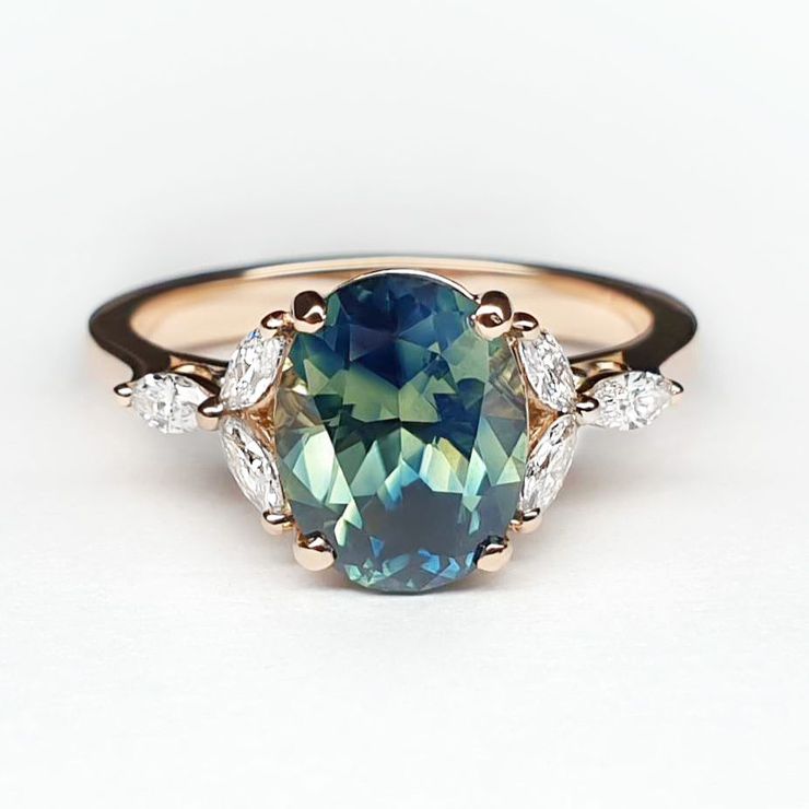 Oval shaped teal bi colour sapphire set in rose gold with marquise accent stones