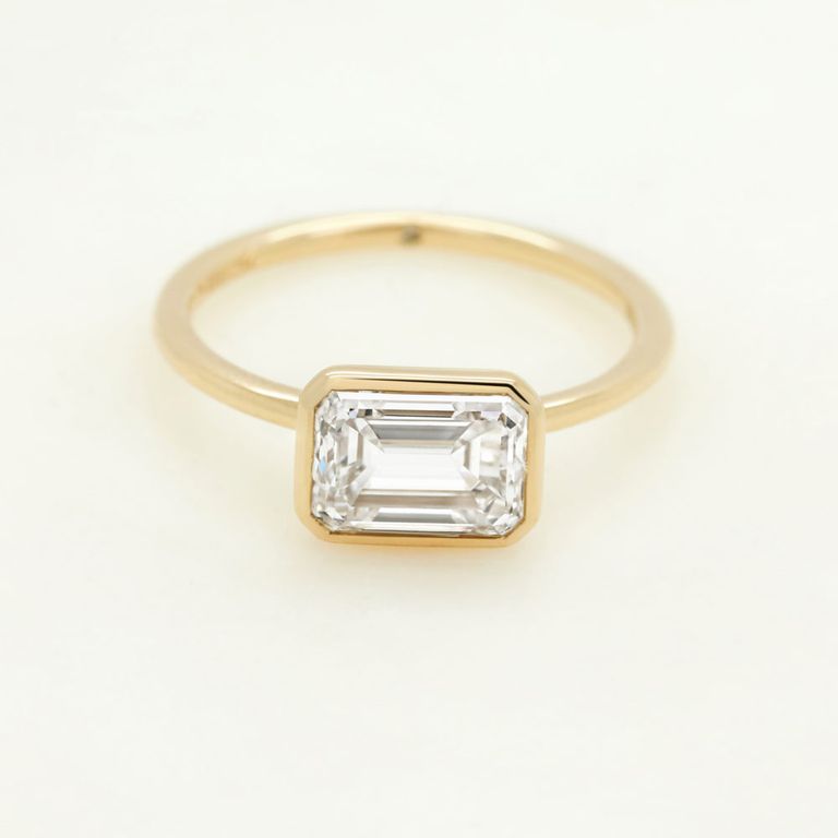 East west emerald diamond bezel set yellow gold ring