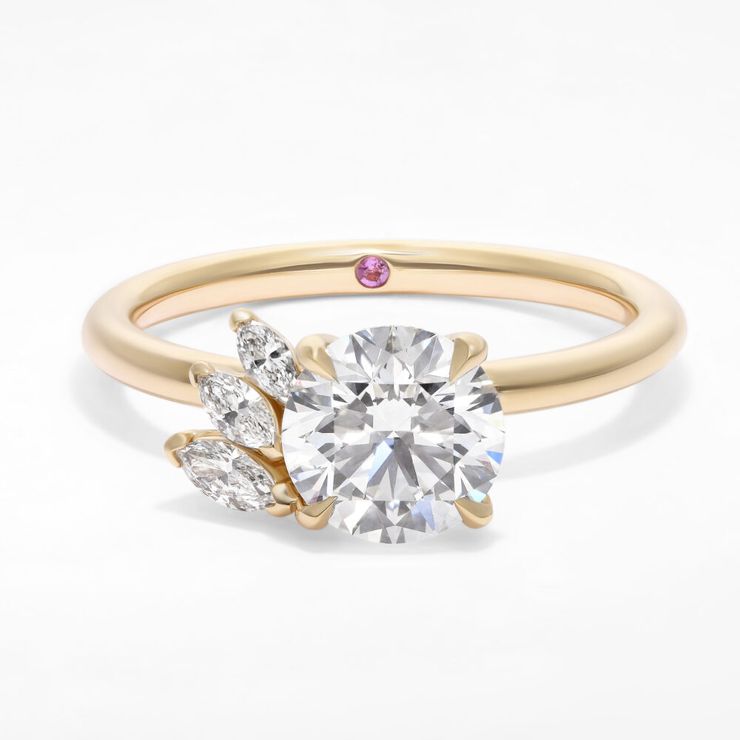 Asymmetric round diamond engagement ring with a partial marquise diamond halo in yellow gold