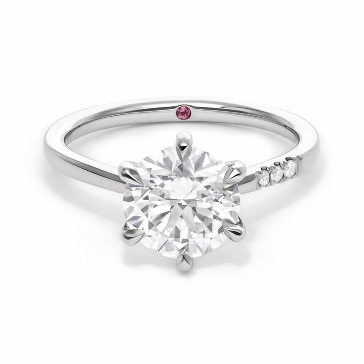 Custom asymmetric platinum engagement ring with round diamond and pavé diamonds on one side of the band