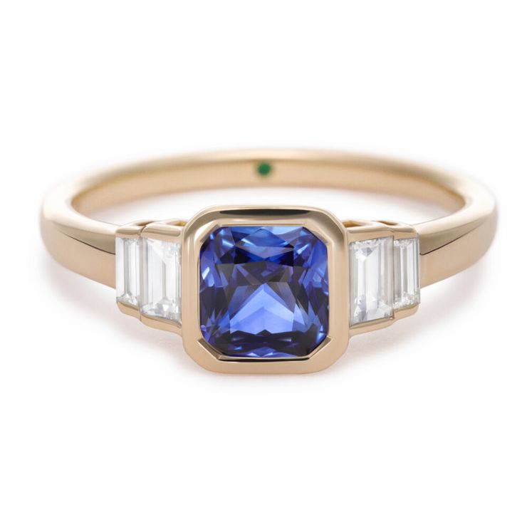 Bezel set vintage inspired yellow gold engagement ring with a square octagonal blue sapphire and diamond baguette side stones