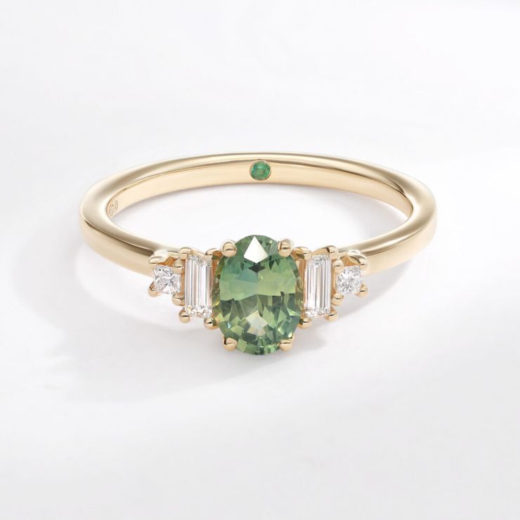 Custom five stone yellow gold engagement ring with green oval sapphire and diamond baguette and princess cut accent stones
