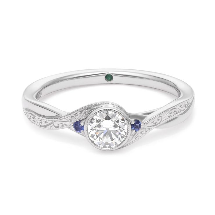 Wave-inspired asymmetric platinum engagement ring with bezel set round diamond and accent blue sapphires and engraving