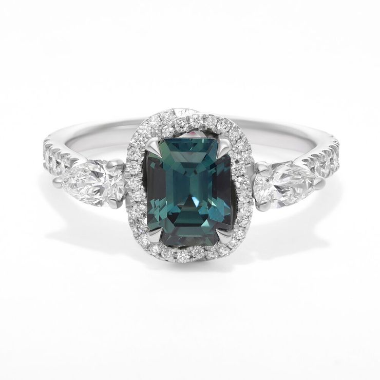 Emerald cut teal sapphire engagement ring with pear side diamonds, diamond twisted halo and pavé band