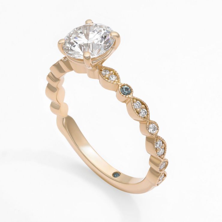 Modified round diamond Selene engagement ring with teal sapphire accent stones set in yellow gold