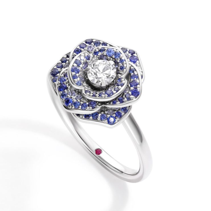 Organic rose inspired blue sapphire petal halo engagement ring with a round diamond centre in platinum