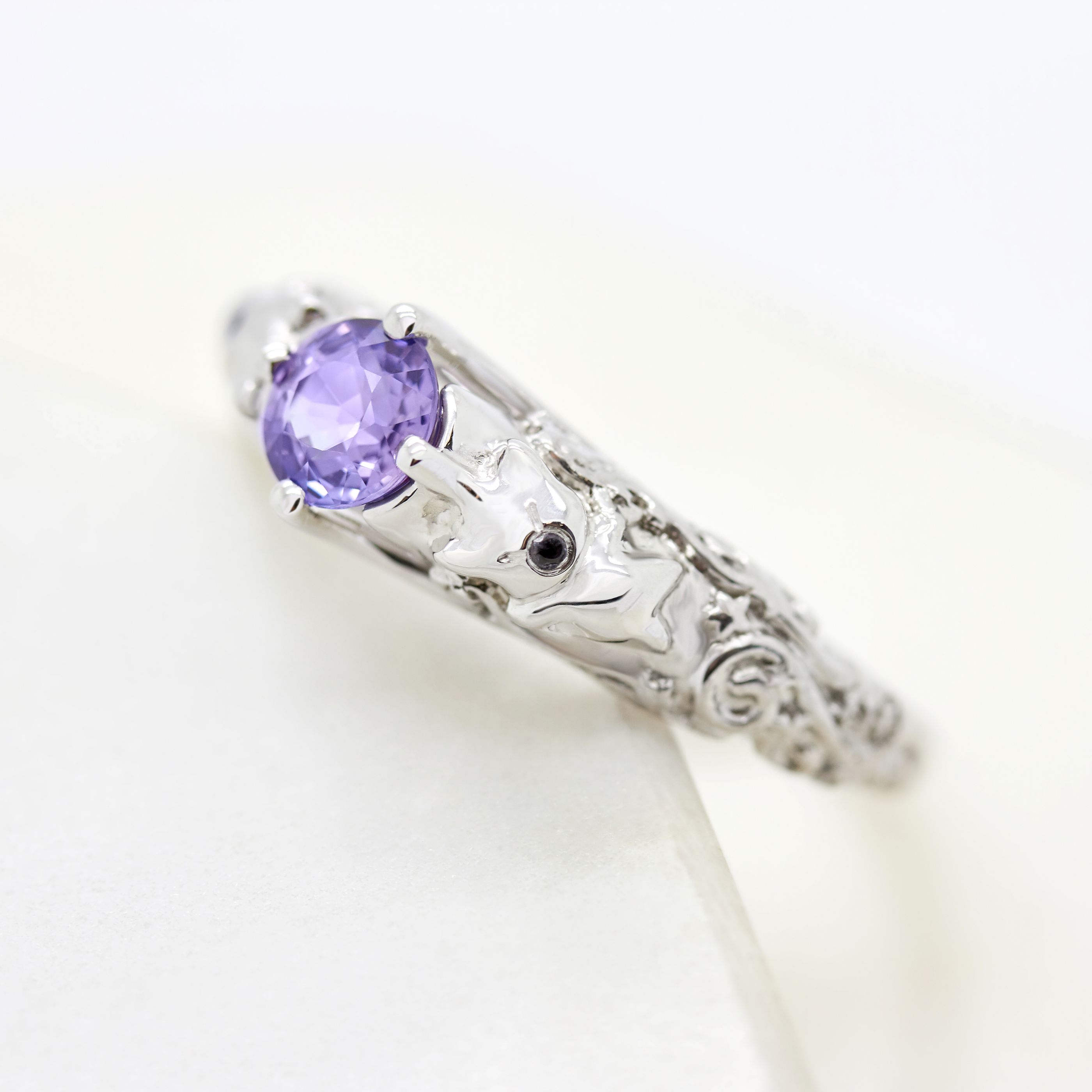 Round purple sapphire set in platinum with filigree detail