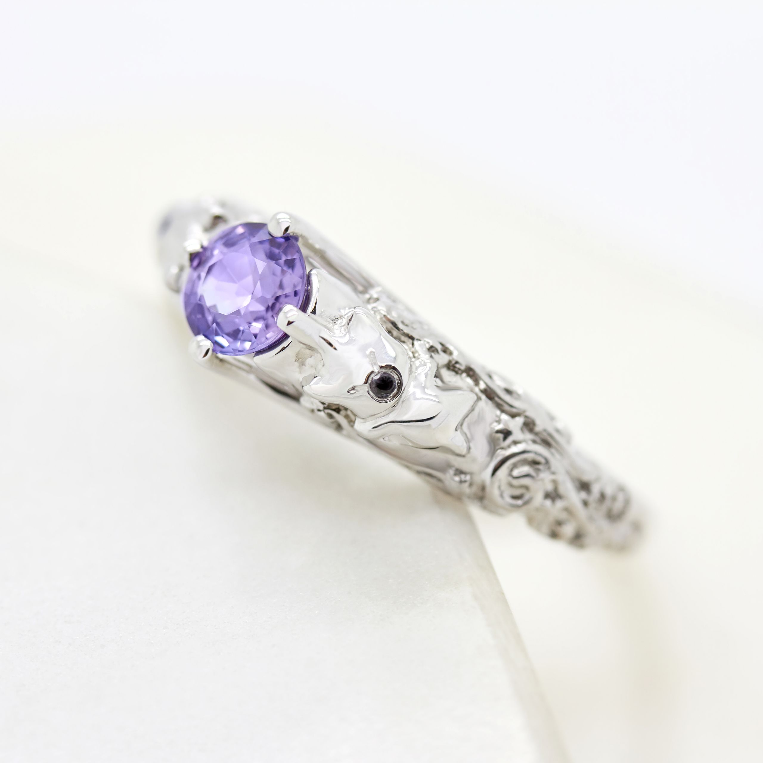 Round purple sapphire set in platinum with filigree detail
