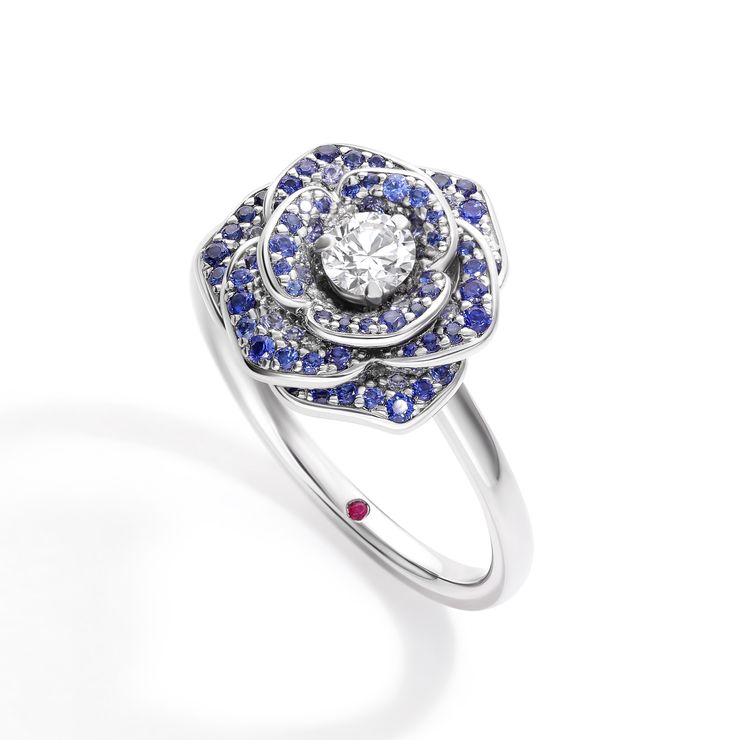 Round diamond centre featuring pavé blue sapphire encrusted rose petal detailing
