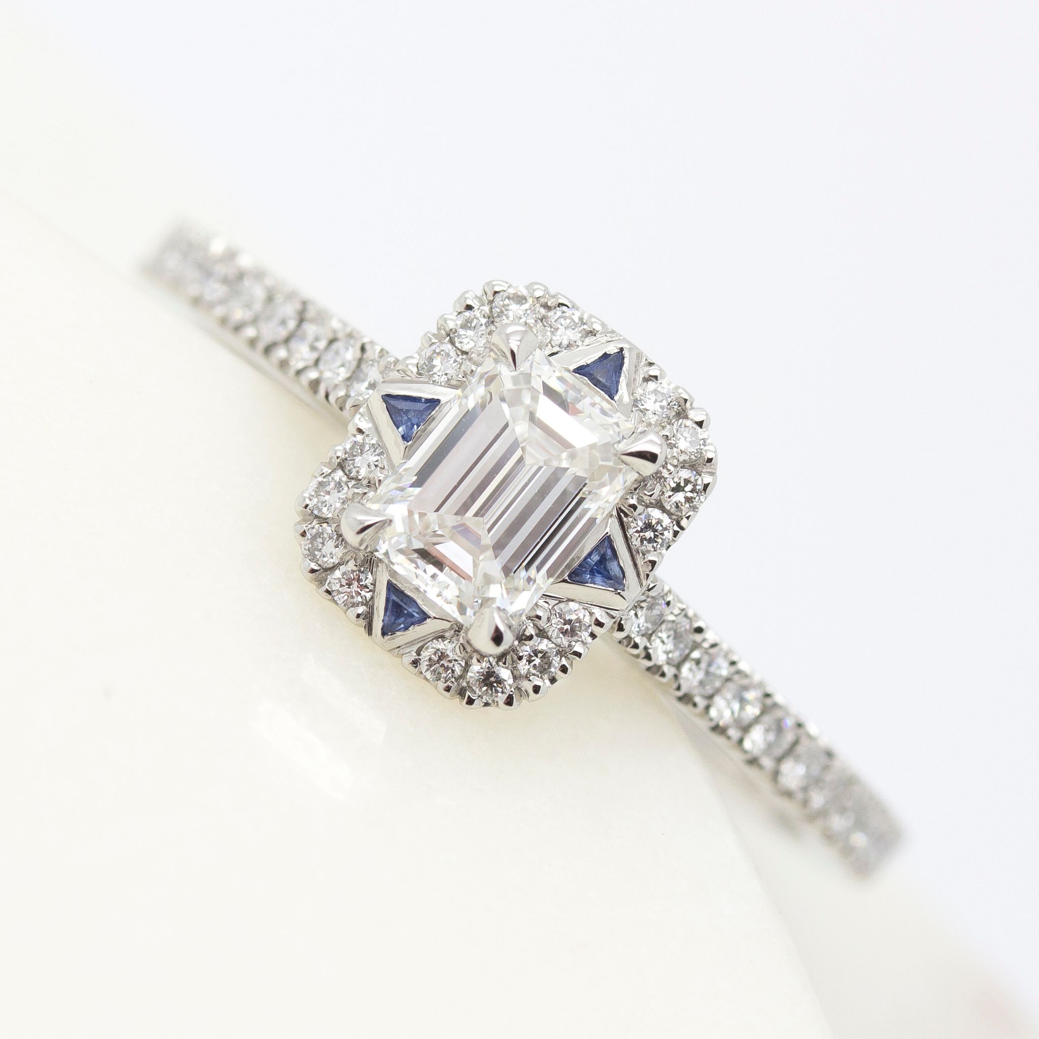 Emerald cut diamond halo engagement ring with trillion blue sapphires