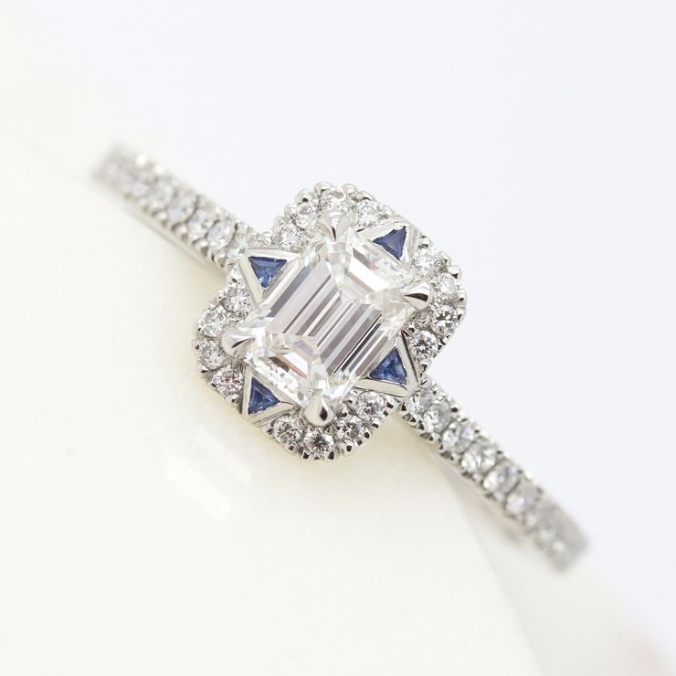 Emerald cut diamond halo engagement ring with trillion blue sapphires