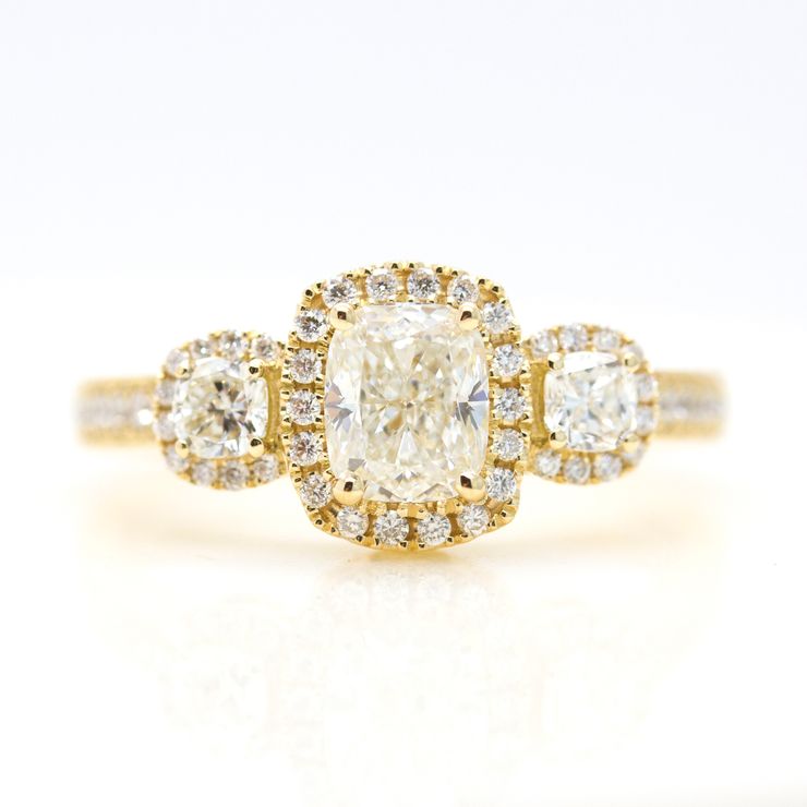 Cushion cut diamond halo trilogy engagement ring in yellow gold