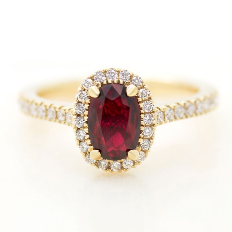 Elongated oval ruby engagement ring with a yellow gold diamond halo