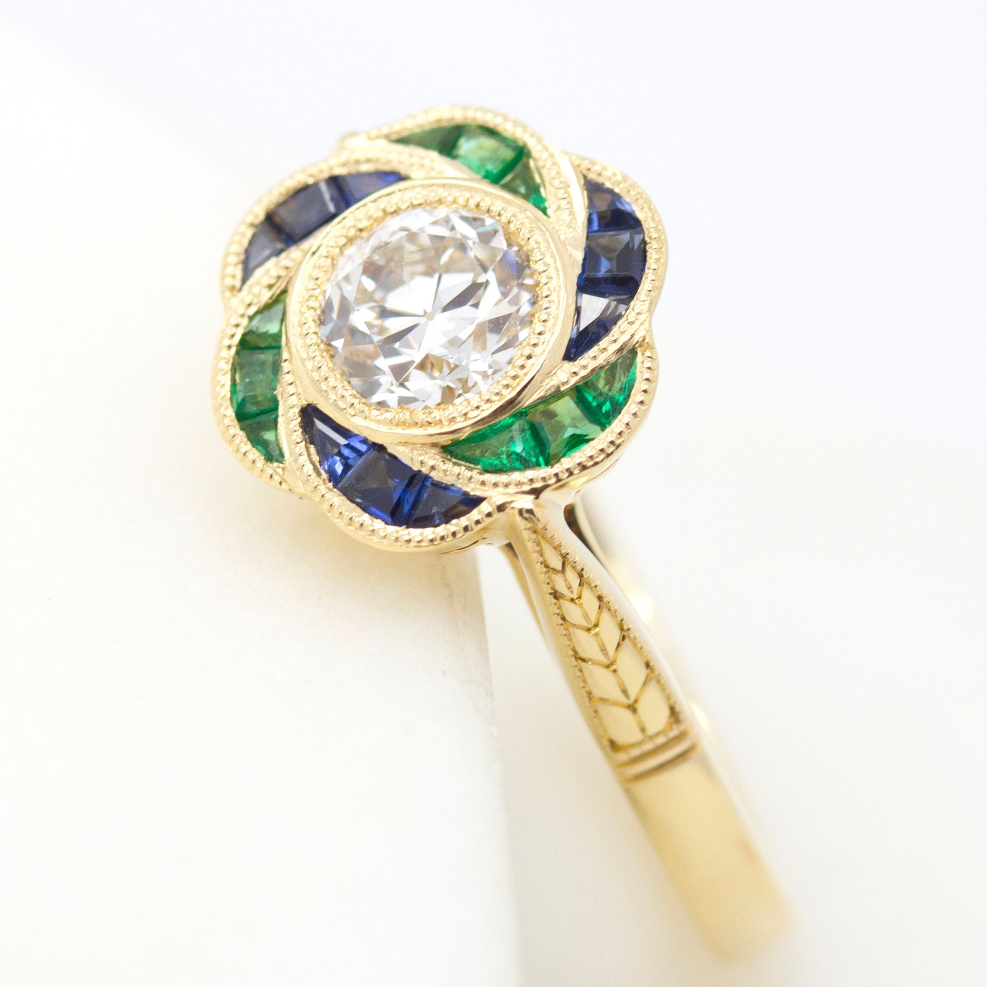 Art Deco inspired custom cut emerald and blue sapphire halo engagement ring