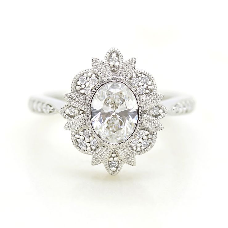 Oval centre diamond engagement ring with milgrain and bead set halo