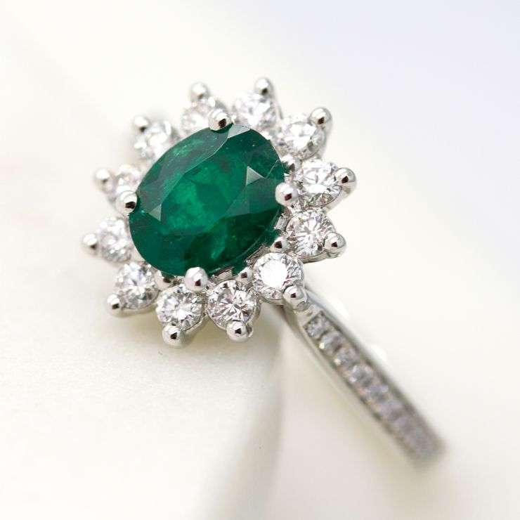 Oval emerald with round diamond halo and diamond bead set engagement ring
