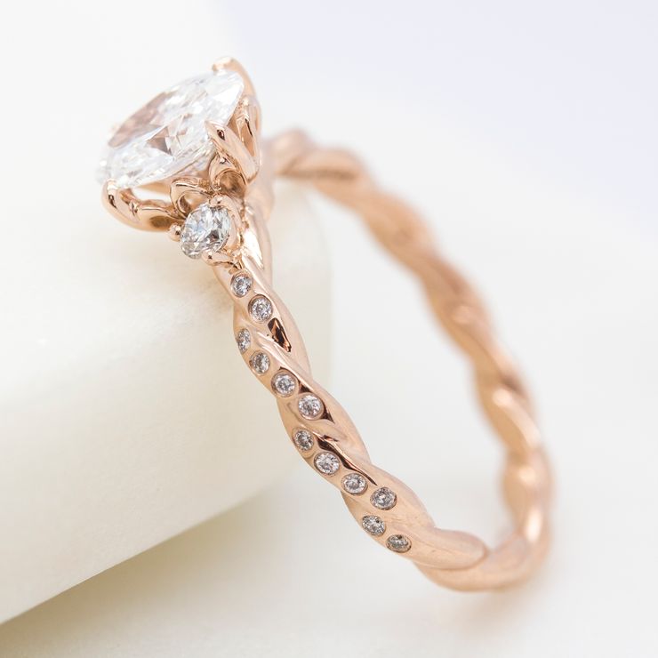 Rose gold twisted engagement ring with bezel set round diamonds