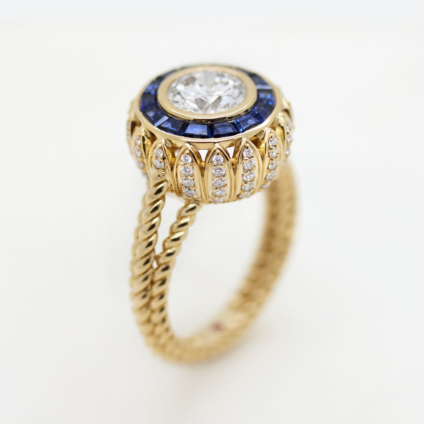 Vintage inspired round diamond with a sapphire halo and a diamond petal basket 