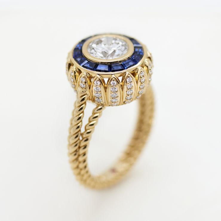Vintage inspired round diamond with a sapphire halo and a diamond petal basket