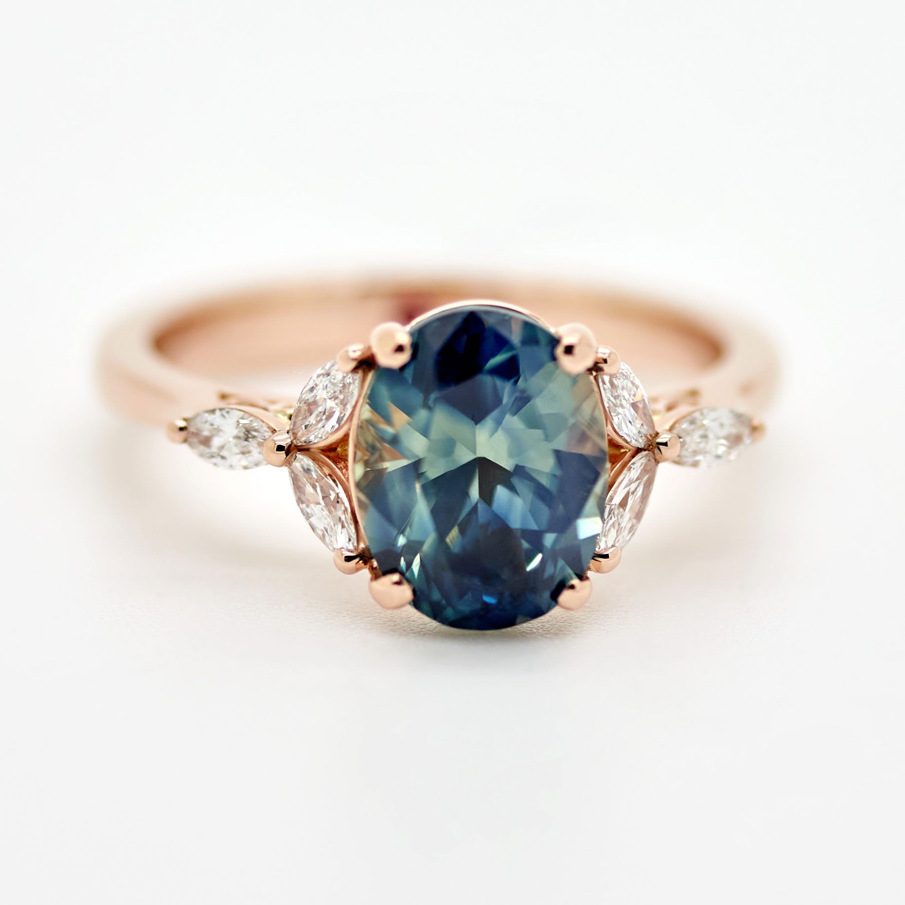 Rose gold engagement ring with a teal oval sapphire