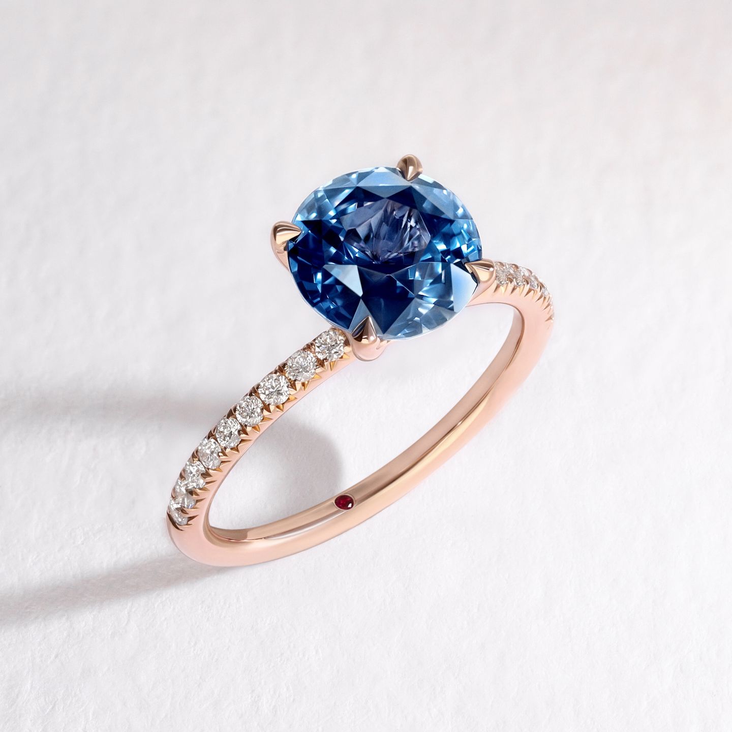 Rose gold diamond pave engagement ring with round blue sapphire centre