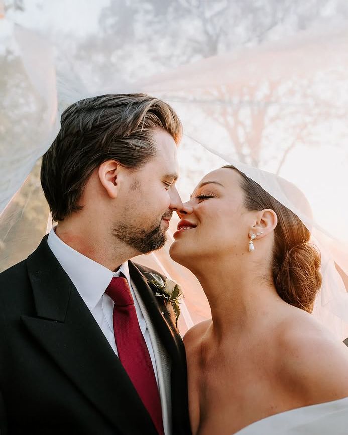 Wedding couple under veil during intimate moment