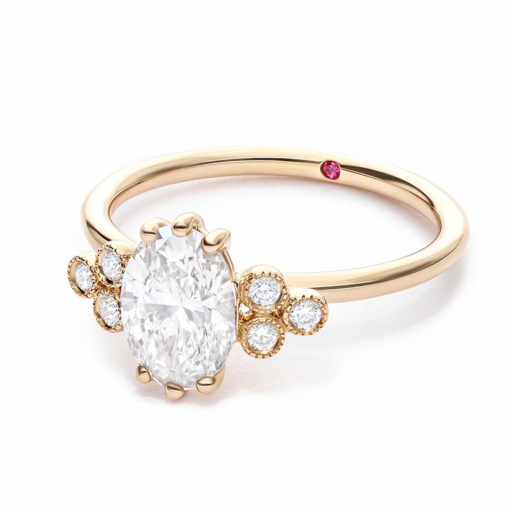 Oval diamond with round diamond accent stones with milgrain detail yellow gold