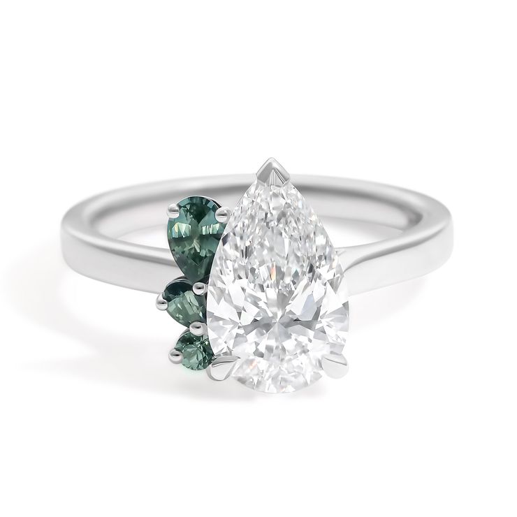 Pear diamond platinum engagement ring with teal green pear accent stones in a half halo cluster
