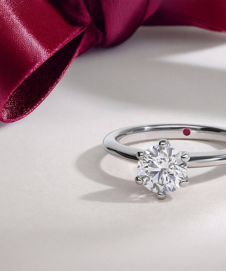 Diamond solitaire engagement ring with red ribbon