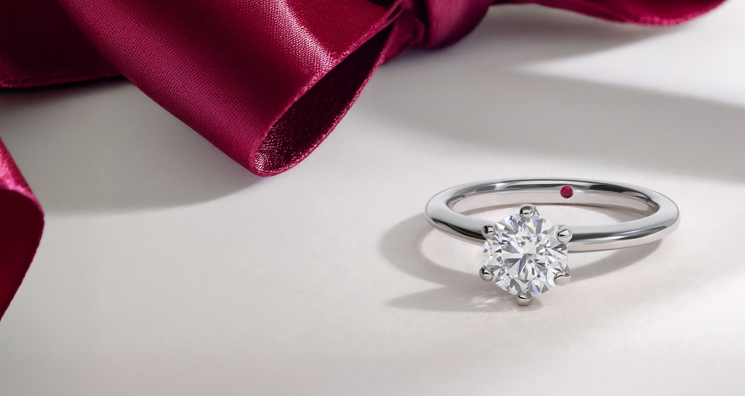Diamond solitaire engagement ring with red ribbon