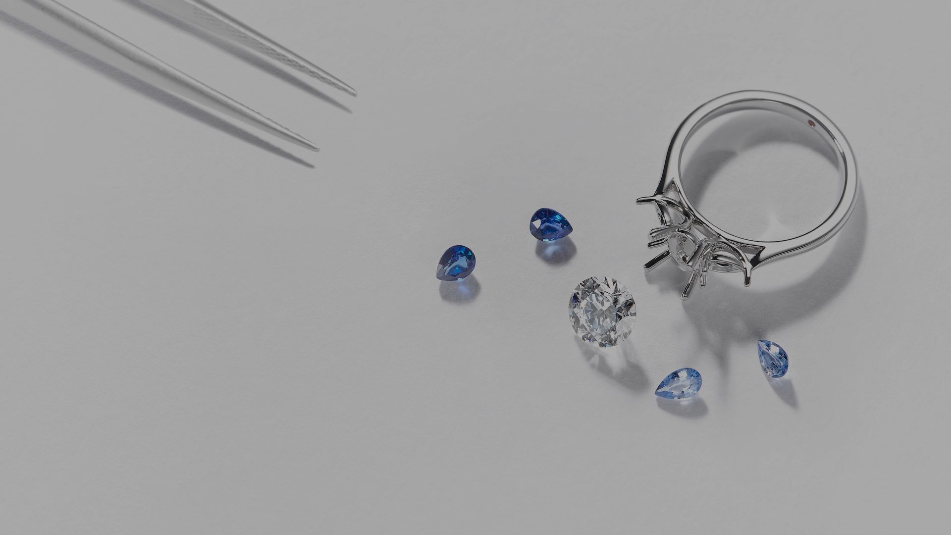 Loose blue sapphire gemstones next to fine jewellery ring